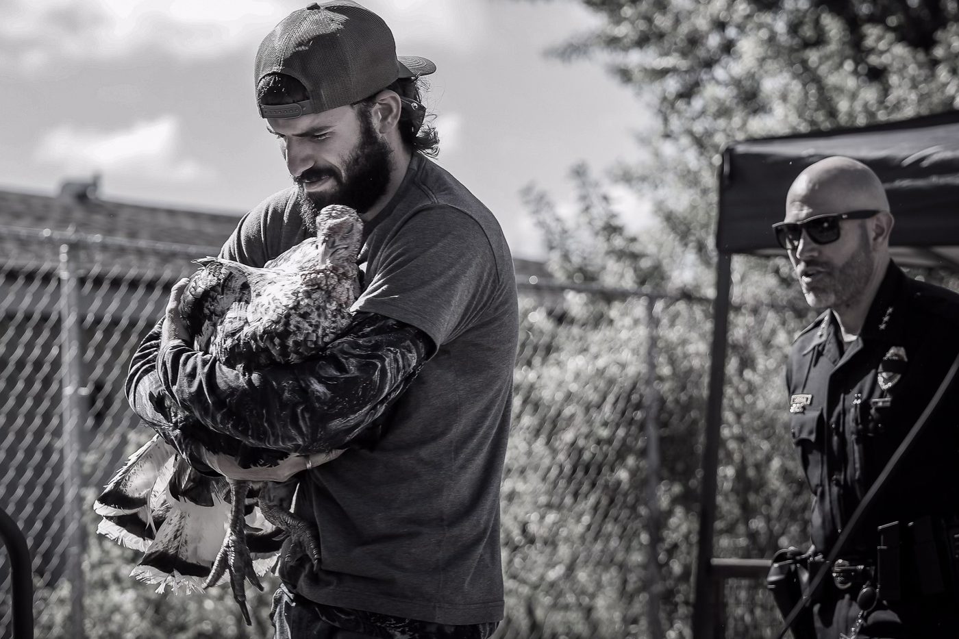 A resident carries a rescued bird as an officer looks on.